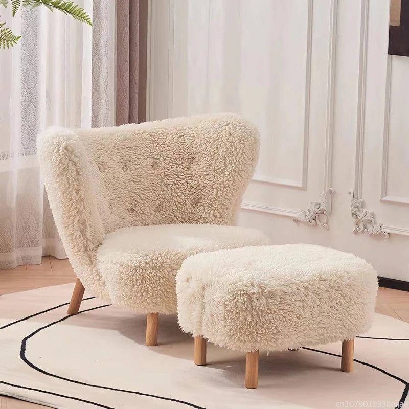 Fluffy beige armchair and ottoman in a room with white curtains and wooden floor.